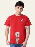 Person wearing a red t-shirt with a logo and playing cards design, holding up a hand with a finger on a beige background. Graphic Red Ace T-Shirt Royal Outfits
