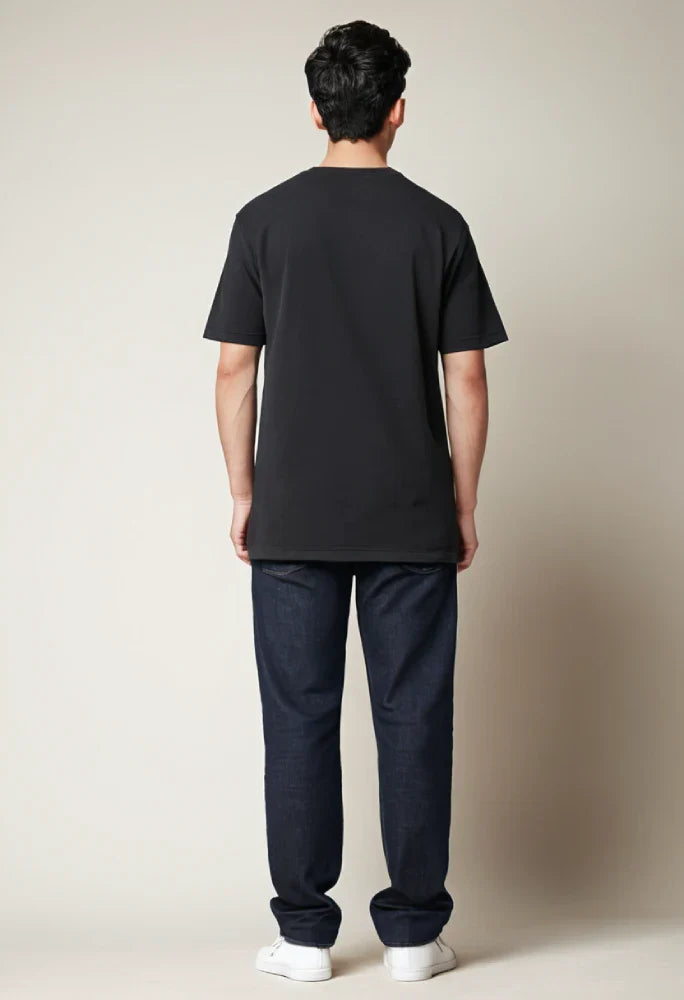 Person wearing a black t-shirt and dark pants against a plain background