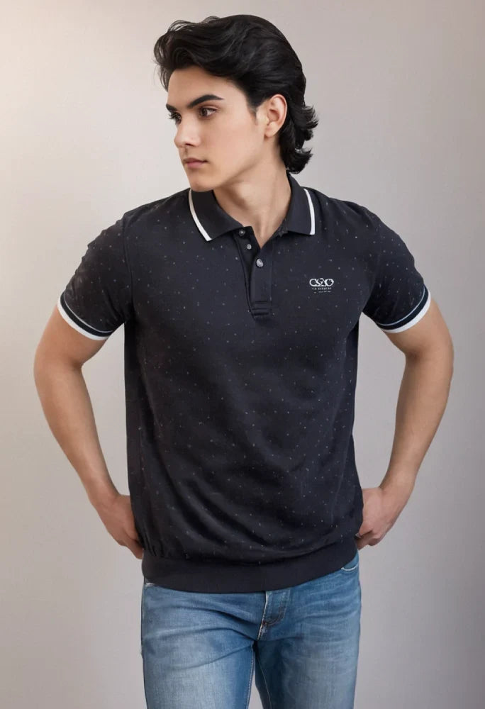 Man wearing a black polo shirt with white trim and a logo, standing against a plain background