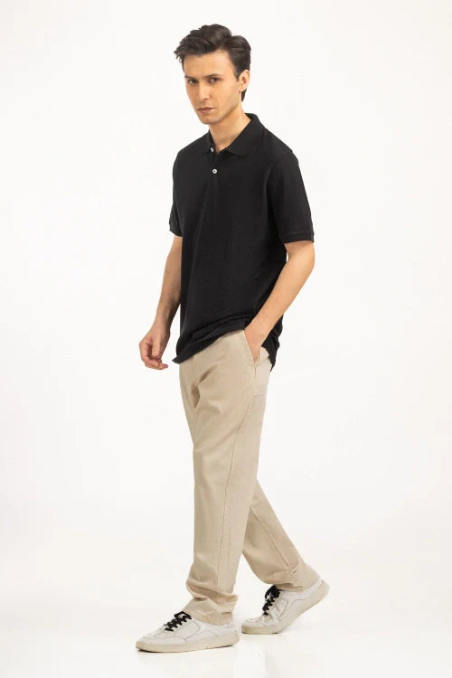 Man wearing a black polo shirt and beige pants on a white background