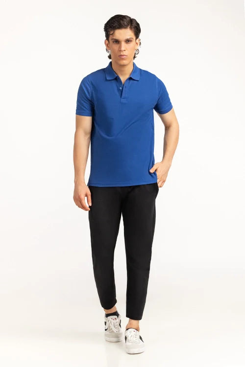 Person wearing a blue polo shirt and black pants on a white background