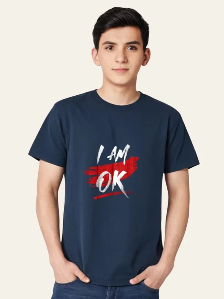 Person wearing a navy blue t-shirt with 'I AM OK' text design on a plain background